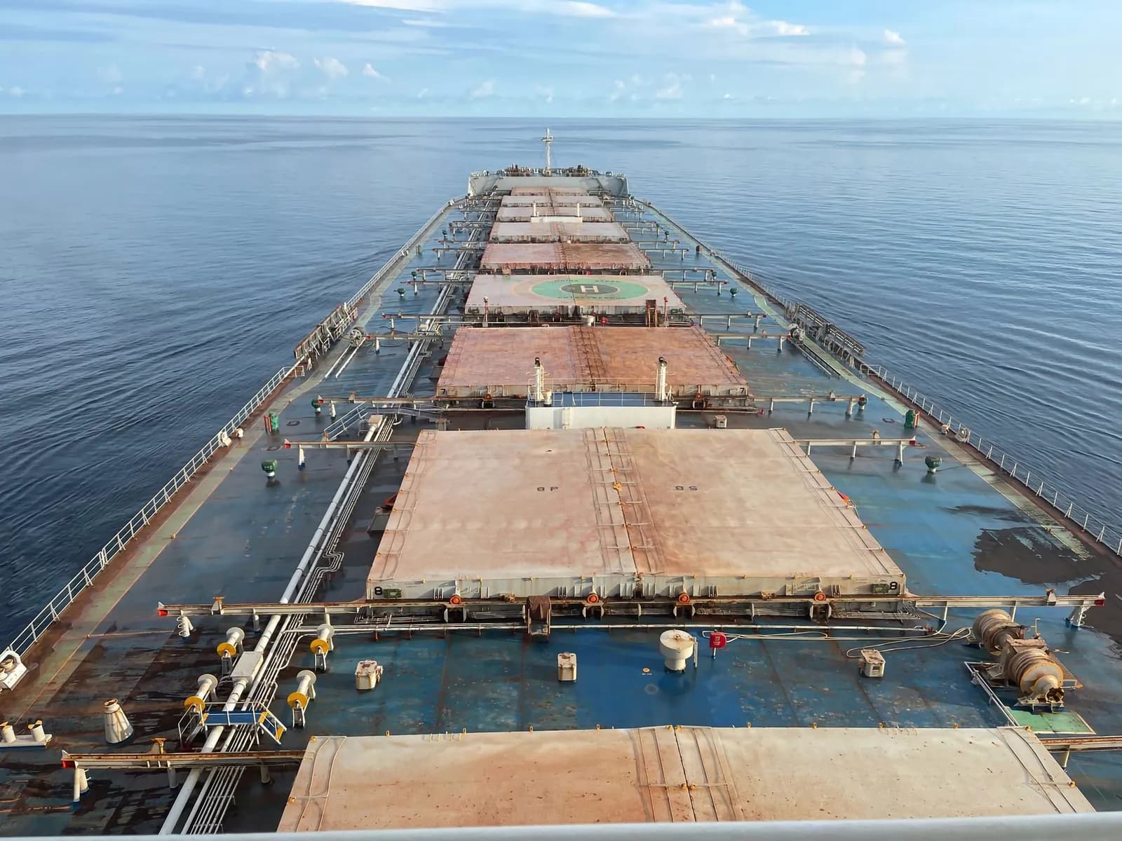 View along the cargo hatches and deck of a bulk carrier from the ship's bridge.